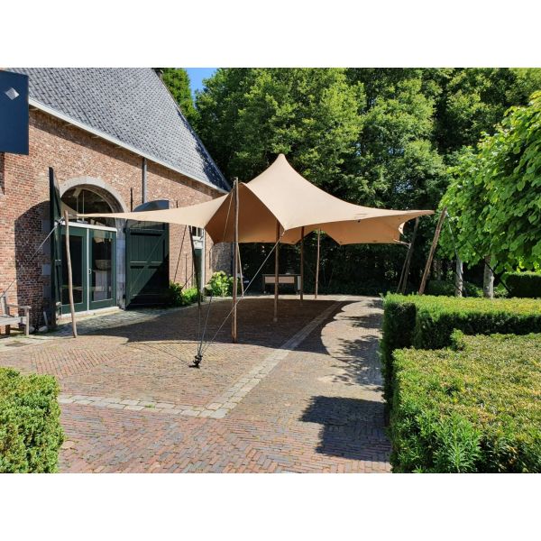 een stretchtent van 6x10,5 meter zit met houten palen vast in de grond. Er staan twee palen in het midden om de gehele tent omhoog te houden. de houten palen zijn vastgezet met touwen en haringen die in de grond zitten.